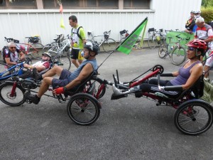 Une féminine amputée des quatre membres sur son handbike tracté par un tricycle à assistance électrique